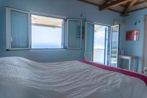 a bedroom with a large white bed with windows at Villa Azul - A Timeless Retreat Above the Aegean in Alonnisos