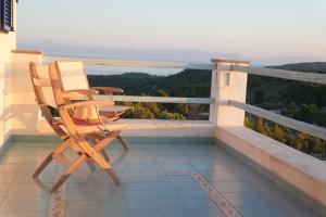 two chairs sitting on a balcony looking out at the water at Villa Azul - A Timeless Retreat Above the Aegean in Alonnisos