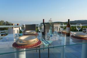 a glass table with wine glasses and wine bottles at Villa Azul - A Timeless Retreat Above the Aegean in Alonnisos +9 photos