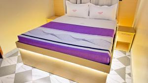 a bedroom with a bed with purple and white sheets at Kent One Hotel in Fort Portal