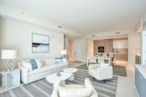 a living room with white furniture and a kitchen at Luxury Ocean View 2BR in Riviera Beach