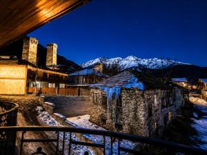 a view of a village at night with snow covered mountains at Hotel Eden Mestia in Mestia