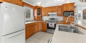 a kitchen with wooden cabinets and a white refrigerator at Cue & couch retreat in Dieppe +6 photos