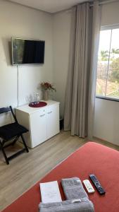 a living room with a couch and a tv and a chair at Villa Serena Garden - Quarto Cama Queen - Banheiro Compartilhado in Cascavel