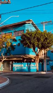 a blue building with a tree in front of it at Pousada Azul do Mar by BlueOcean in Arraial do Cabo