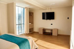a bedroom with a bed and a television on the wall at QAIPU HOTEL in Puquio