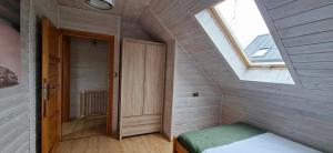 a small attic room with a bed and a window at Domki Malibu in Tupadła