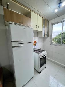 a kitchen with a white refrigerator and a stove at 08 - Apê próximo ao Metrô e Centro com Wi-Fi e Ar condionado in São Leopoldo