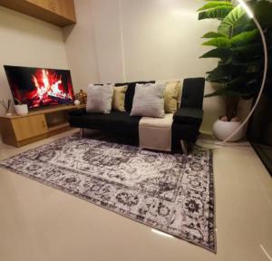 a living room with a black couch and a rug at The Coastal Luxe Suite in Samal