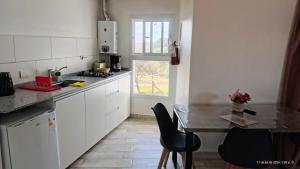 a kitchen with white cabinets and a table with chairs at Cabañas Altos del Sauce in Villa General Belgrano