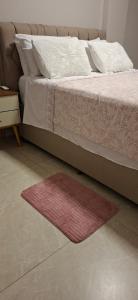 a bedroom with a bed with a red rug next to it at Flat Praia da Costa in Vila Velha