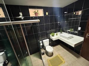a black tiled bathroom with a toilet and a sink at Salvador Backpackers House in Salvador +37 photos