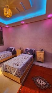 two beds in a room with purple lights at VibeLine Surf Camp in Tamraght Ouzdar +3 photos