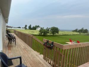 a deck with chairs and a yard with a field at Le Campagnard in Matane