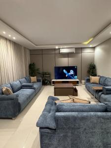 a living room with blue couches and a flat screen tv at شاليهات دبليو العمارية in Al ‘Ammārīyah