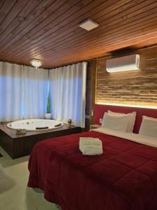 a bedroom with a large bed and a bath tub at Chales Vidal in Venda Nova do Imigrante