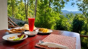 a wooden table with plates of food and a drink at Ella Pine Crest in Ella