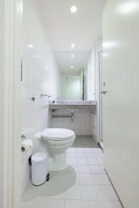 a white bathroom with a toilet and a sink at Princes Gardens in London