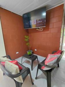 a living room with two chairs and a tv at Hotel GinaMar Ladrilleros in Buenaventura