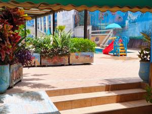 a swimming pool with potted plants and a playground at Villa Drayd in Ait Melloul