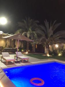 a swimming pool with two chairs and an umbrella at شاليهات دبليو العمارية in Al ‘Ammārīyah