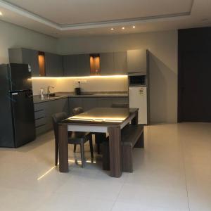 a kitchen with a table with chairs and a refrigerator at شاليهات دبليو العمارية in Al ‘Ammārīyah