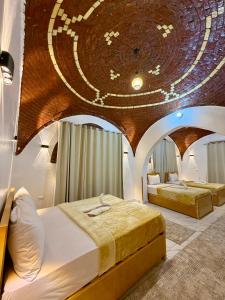 two beds in a room with a large ceiling at Al-Sultan Hotel in Al Aqālitah