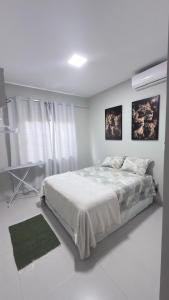 a white bedroom with a bed and a window at Lar doce lar in Paragominas