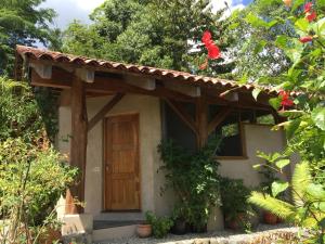 Una pequeña casa con una puerta de madera en un jardín en Puri Mas OSA Eco-Retreat, en Barrigones