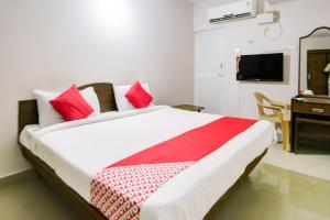a bedroom with a large bed and a desk at Hotel O Ksp Lodge in Neyveli