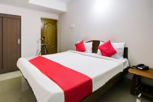 a bedroom with a large bed with red and white pillows at Hotel O Ksp Lodge in Neyveli