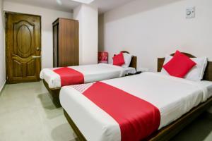 two beds in a room with red and white sheets at Hotel O Ksp Lodge in Neyveli