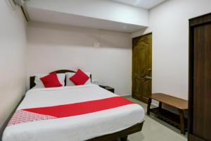 a bedroom with a bed with red pillows and a desk at Hotel O Ksp Lodge in Neyveli +19 photos