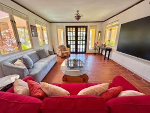a living room with a red couch and a flat screen tv at Villa De Palma -Oceanfront community w generator in Sabana