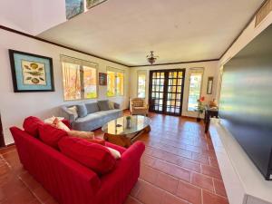 a living room with a red couch and a table at Villa De Palma -Oceanfront community w generator in Sabana