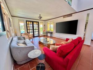 a living room with red couches and a flat screen tv at Villa De Palma -Oceanfront community w generator in Sabana