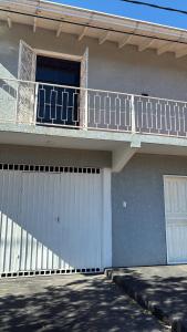 a house with a white fence and a balcony at Áurea hospedagem in Ciudad del Este