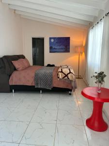 a bedroom with a bed and a red table at Áurea hospedagem in Ciudad del Este