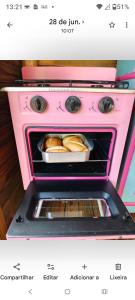 a pink oven with a pan of bread in it at Recanto Duas Rosas in Venda Nova do Imigrante