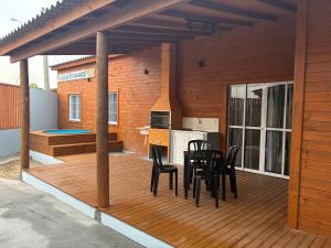 a wooden deck with a table and chairs on it at Casa Dunas - Las Caracolas - Cassino RS in Rio Grande