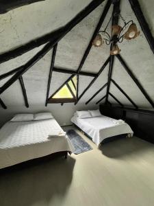 a attic bedroom with two beds and a window at Cabaña La Colina in Sutatausa