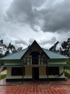 a house with a green roof on top of it at Cabaña La Colina in Sutatausa