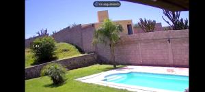 a swimming pool in a yard next to a wall at Quincho Ruben in La Rioja