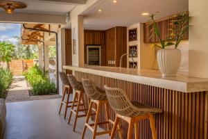 an outdoor kitchen with a bar with stools at Villa Florens in Jericoacoara