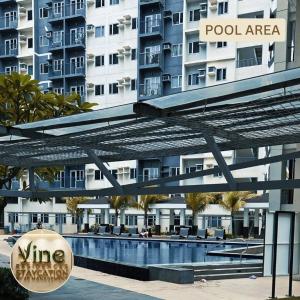 a hotel with a swimming pool in front of a building at Vine Residences Staycation in Manila