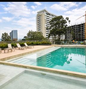 a swimming pool with chairs and a building at Apartamento Armenia in Armenia