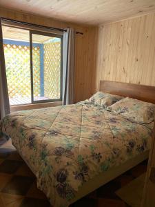 a bed in a room with a large window at Casa Salto Pichi Ignao in Lago Ranco