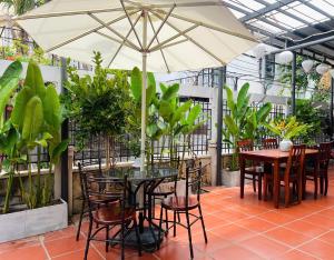 a patio with tables and chairs and an umbrella at Old Lane Homestay in Hoi An