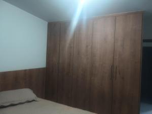 a bedroom with a wooden cabinet and a bed at Casa Aconchegante in Barbacena