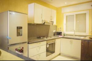 a kitchen with a stainless steel refrigerator and white cabinets at Immeuble carrefour 2 in Ngaparou